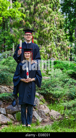 Junges Paar in der Graduierung Tag posiert im Freien in einem schönen grünen Garten. Stockfoto