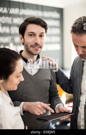 Porträt von zuversichtlich Geschäftsmann verklagt digital-Tablette mit Kollegen im Büro Stockfoto