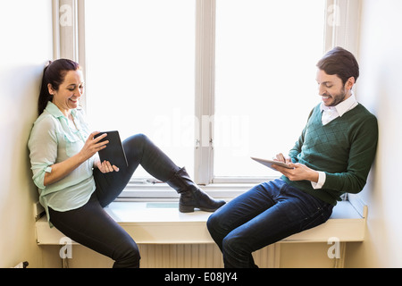 Lächelnde Geschäftsleute mit digital-Tablette auf der Fensterbank im Büro Stockfoto