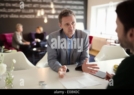 Unternehmer, die während der Diskussion mit männlicher Kollege am Schreibtisch gestikulieren Stockfoto