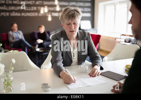 Senior Geschäftsfrau auf Dokument am Schreibtisch zu schreiben Stockfoto