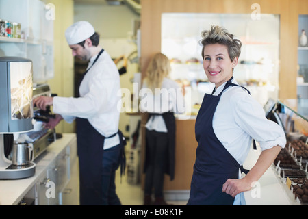 Porträt des Lächelns weibliche Café-Besitzer mit Kollegen im Hintergrund arbeitet Stockfoto