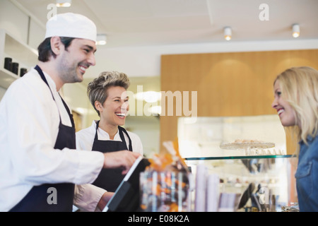 Glückliche Arbeitnehmer behandelnden Kundin am Café-Schalter Stockfoto