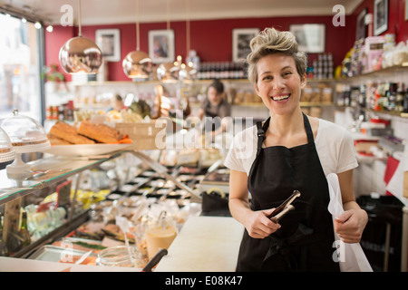 Porträt von glücklich Verkäuferin schneiden Käse am Schalter im Supermarkt Stockfoto