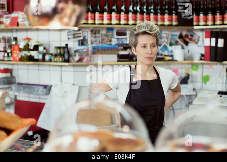 Verkäuferin Weg schauen, während Sie im Supermarkt stehen Stockfoto