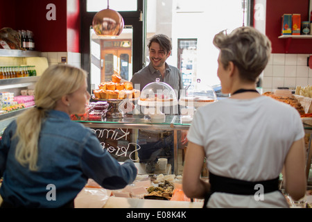 Rückansicht des Verkäuferinnen mit Kunden stehen am Schalter im Supermarkt Stockfoto