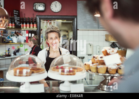 Lächelnden Verkäuferin anwesenden Kunden im Supermarkt Stockfoto