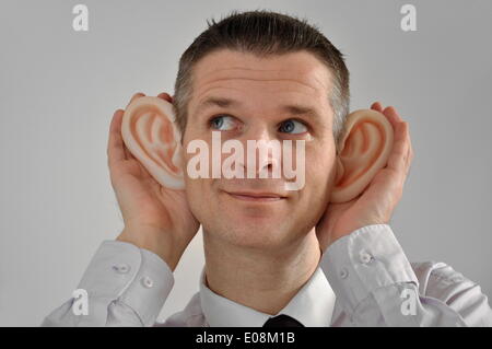 Illustration - Ein Mann mit riesigen Gummi-Ohren spioniert die Umgebung in Deutschland aus, 27. Februar 2011. Fotoarchiv für Zeitgeschichte - KEIN KABELDIENST Stockfoto