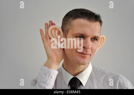 Illustration - Ein Mann mit riesigen Gummi-Ohren spioniert die Umgebung in Deutschland aus, 27. Februar 2011. Fotoarchiv für Zeitgeschichte - KEIN KABELDIENST Stockfoto