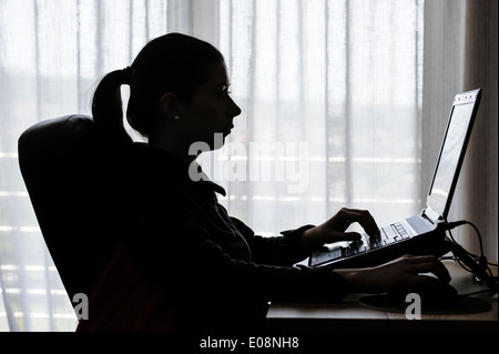 Silhouette einer jungen Frau mit einem Laptop-Computer zu Hause Stockfoto
