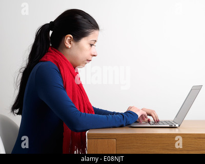 Seitenansicht einer jungen Frau mit einem Laptop-Computer auf einen Schreibtisch aus Holz Stockfoto