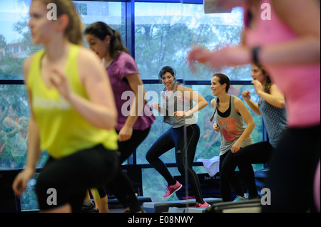 Junge Frau, die Spaß haben, während ein Schritt-Aerobic-Fitness-Kurs in der Turnhalle Stockfoto