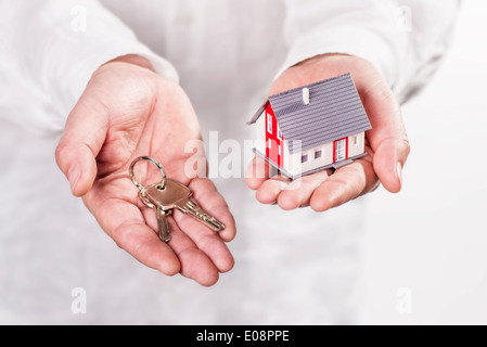 Hände halten ein Haus und Schlüssel. Stockfoto