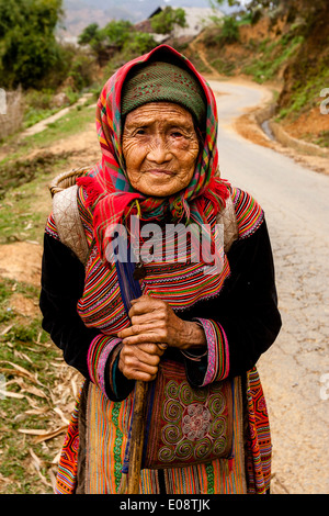 Eine ältere Frau aus dem Stamm der Flower Hmong Hill auf dem Weg zum Wochenmarkt In können Cau, Provinz Lao Cai, Vietnam Stockfoto