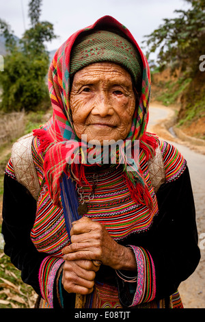 Eine ältere Frau aus dem Stamm der Flower Hmong Hill auf dem Weg zum Wochenmarkt In können Cau, Provinz Lao Cai, Vietnam Stockfoto