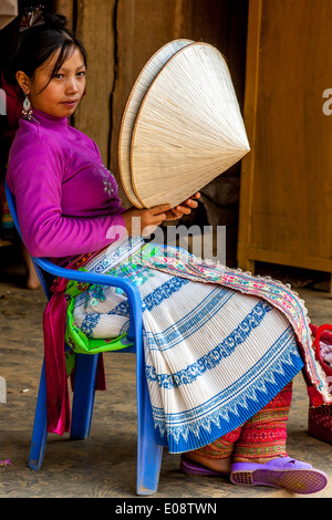 Eine junge Frau aus der Flower Hmong Bergstämme verkaufen Hüte auf dem ethnischen Wochenmarkt In Coc Li, Provinz Lao Cai, Vietnam Stockfoto