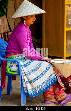 Eine junge Frau aus der Flower Hmong Bergstämme verkaufen Hüte auf dem ethnischen Wochenmarkt In Coc Li, Provinz Lao Cai, Vietnam Stockfoto