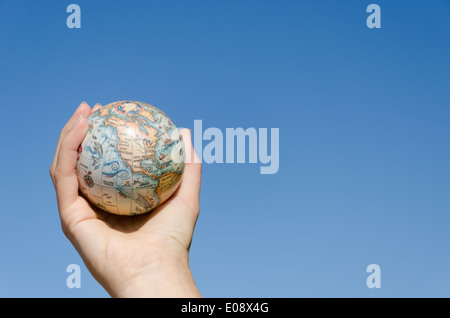 stilisierte globale Erde Modell Spielzeug in der Hand auf blauen Himmelshintergrund, Nordamerika Kontinent Stockfoto