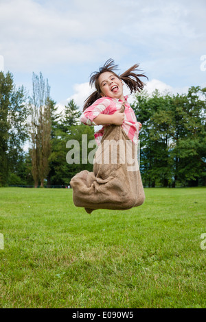 Mädchen in einem Sackleinen Sackhüpfen Stockfoto