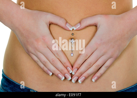 Eine Frau hat Magenschmerzen oder Bauchschmerzen. Hände in Herzform um Nabel Piercing., Eine Frau Hut 4.SP Oder Magenschm Stockfoto