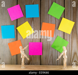 zwei hölzerne Puppe Mann mit Wand voller post-it Papiere Stockfoto