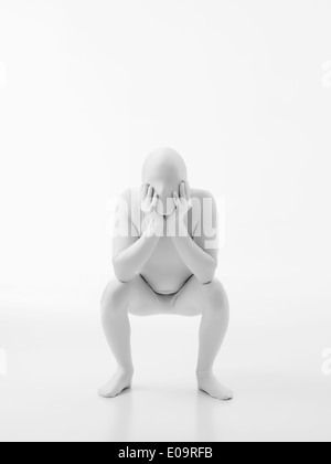 der Mann ohne Gesicht in weiß gekleidet mit Hände auf seine Wangen sitzt in einer Sitzposition Stockfoto
