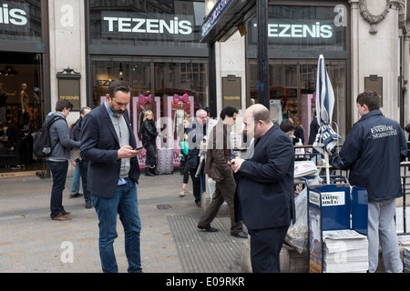 Menschen auf ihren Mobiltelefonen in Londons wichtigste Einkaufsstraße Oxford Street Stockfoto