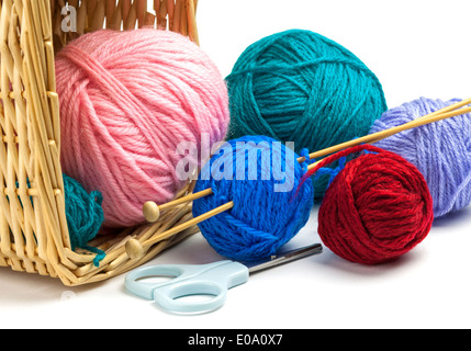Bunte Fäden aus Korb, Stricknadel und Schere isoliert auf weißem Hintergrund fallen Stockfoto