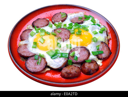 Spiegeleier mit Würstchen und grüne Zwiebeln in einer roten Platte isoliert auf weißem Hintergrund Stockfoto