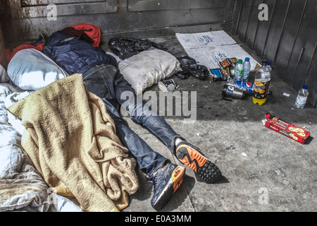 Tramp schlafen in einem Türrahmen, mit Decke mit Müll umgeben; in London, UK. Obdachlose in Großbritannien. Stockfoto