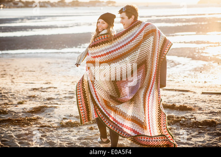 Paar, eingewickelt in eine Decke, ein Spaziergang am Strand Stockfoto