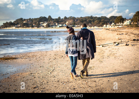 Romantische Pärchen spazieren am Strand Stockfoto