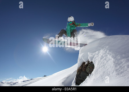 Junge Frau springen mit Snowboard, Mayrhofen, Tirol, Österreich Stockfoto