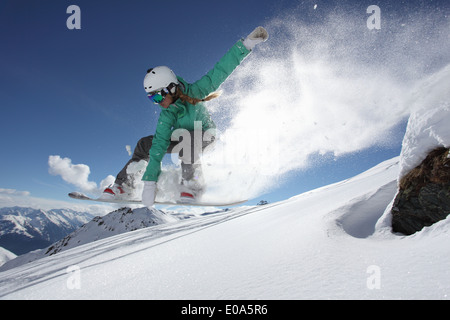 Junge Frau springt auf Snowboard, Mayrhofen, Tirol, Österreich Stockfoto