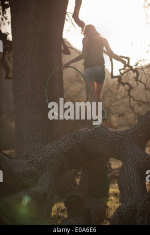 Junge Frau balancieren auf umgestürzten Baum mit Hoola Hoop, Malibu Creek State Park, Kalifornien, USA Stockfoto