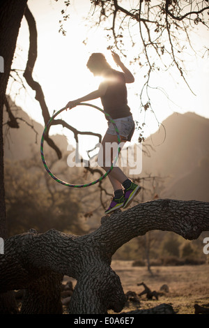 Junge Frau balancieren auf Zweig mit Hoola Hoop, Malibu Creek State Park, Kalifornien, USA Stockfoto