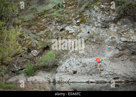 Junger Mann Klettern auf Felsen am See, Malibu Creek State Park, Kalifornien, USA Stockfoto