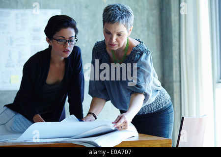 Zwei Geschäftsfrauen Überprüfung Blaupausen im Büro Stockfoto