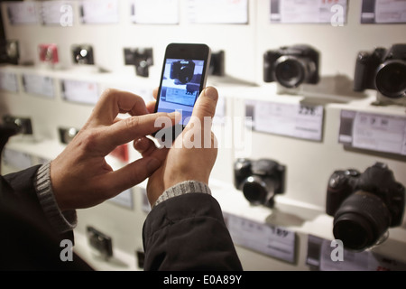 Mitte erwachsener Mann Fotografieren im Fotogeschäft zeigen Sie mit Smartphone an Stockfoto