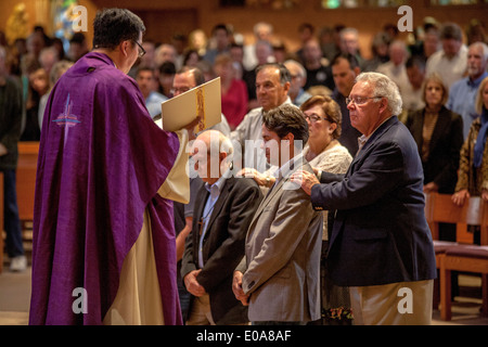 Katechumenen oder Menschen, die Katholiken, werden Knien mit ihren Sponsoren vor eine Robe vietnamesische amerikanische Priester für die Prüfung in einer katholischen Kirche in Laguna Niguel, CA. Stockfoto