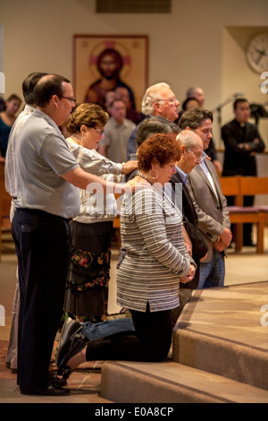 Katechumenen oder Menschen, die Katholiken, werden Knien mit ihren Sponsoren vor einem Priester für die Prüfung in einer katholischen Kirche in Laguna Niguel, CA. Stockfoto