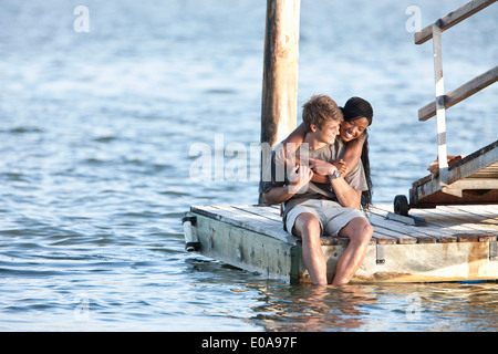 Junges Paar sitzt am Steg Stockfoto