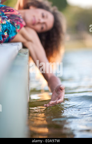 Junge Frau am Steg, Hand berühren Wasser Stockfoto