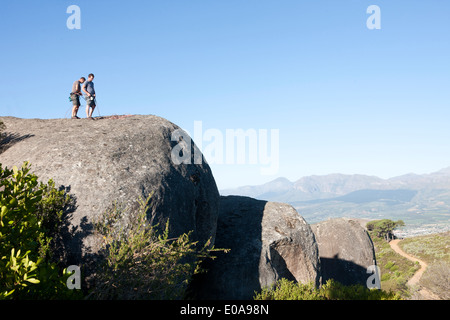 Junge männliche Bergsteiger anbringen, Seile und Gurte auf Felsen Stockfoto