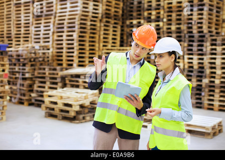 Männliche und weibliche Führungskräfte mit digital-Tablette im Auslieferungslager Stockfoto