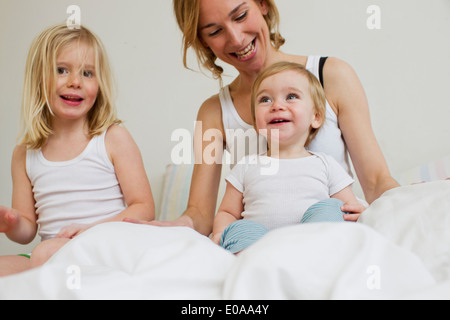 Porträt von Mitte Erwachsene Frau im Bett mit zwei Töchtern Stockfoto