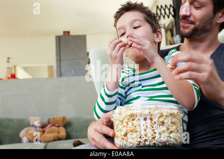 Vater und Sohn teilen Popcorn im Wohnzimmer