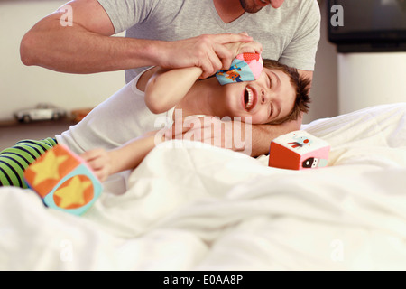 Vater und seinem kleinen Sohn spielen mit Bausteinen auf Bett Stockfoto