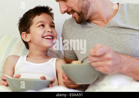 Vater und seinem kleinen Sohn beim Frühstück im Bett Stockfoto