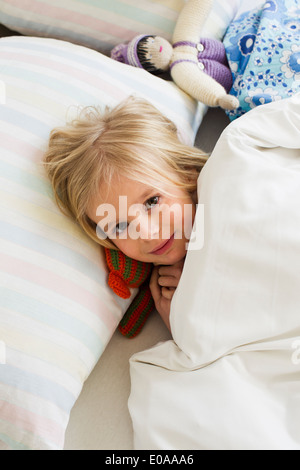 Porträt des jungen Mädchens liegen im Bett mit Puppe Stockfoto